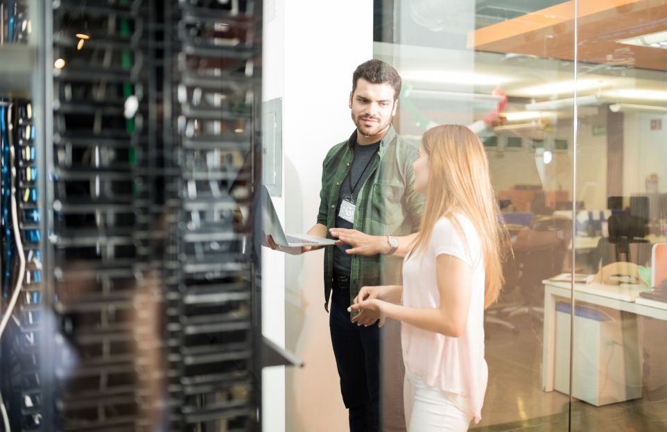 two coworkers looking at a  laptop in server room